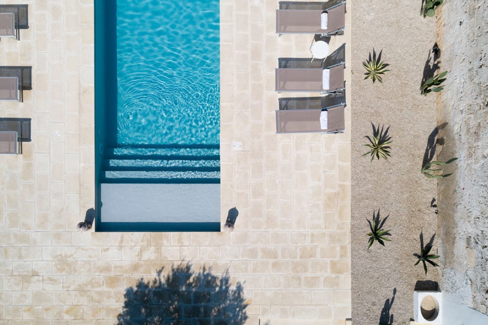 La piscina del Relais vista dall'alto, tra pietra chiara e agavi
