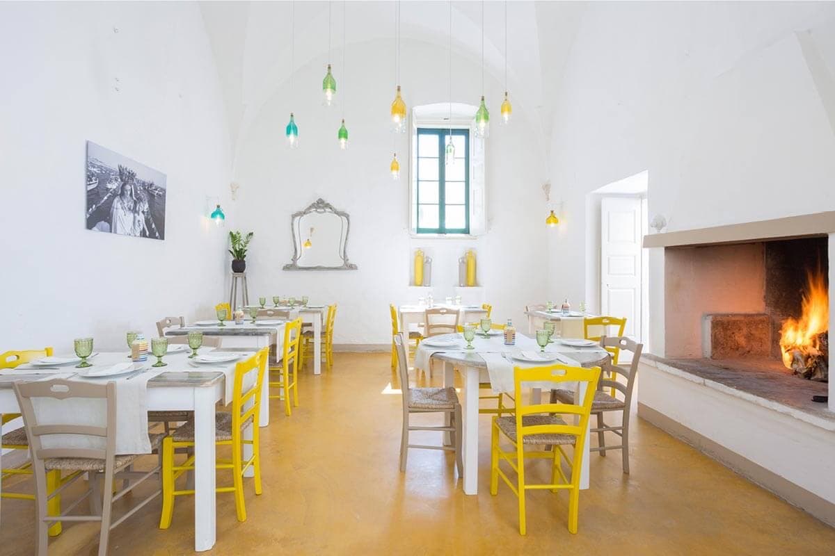 La sala da pranzo bianca con sedie gialle e camino